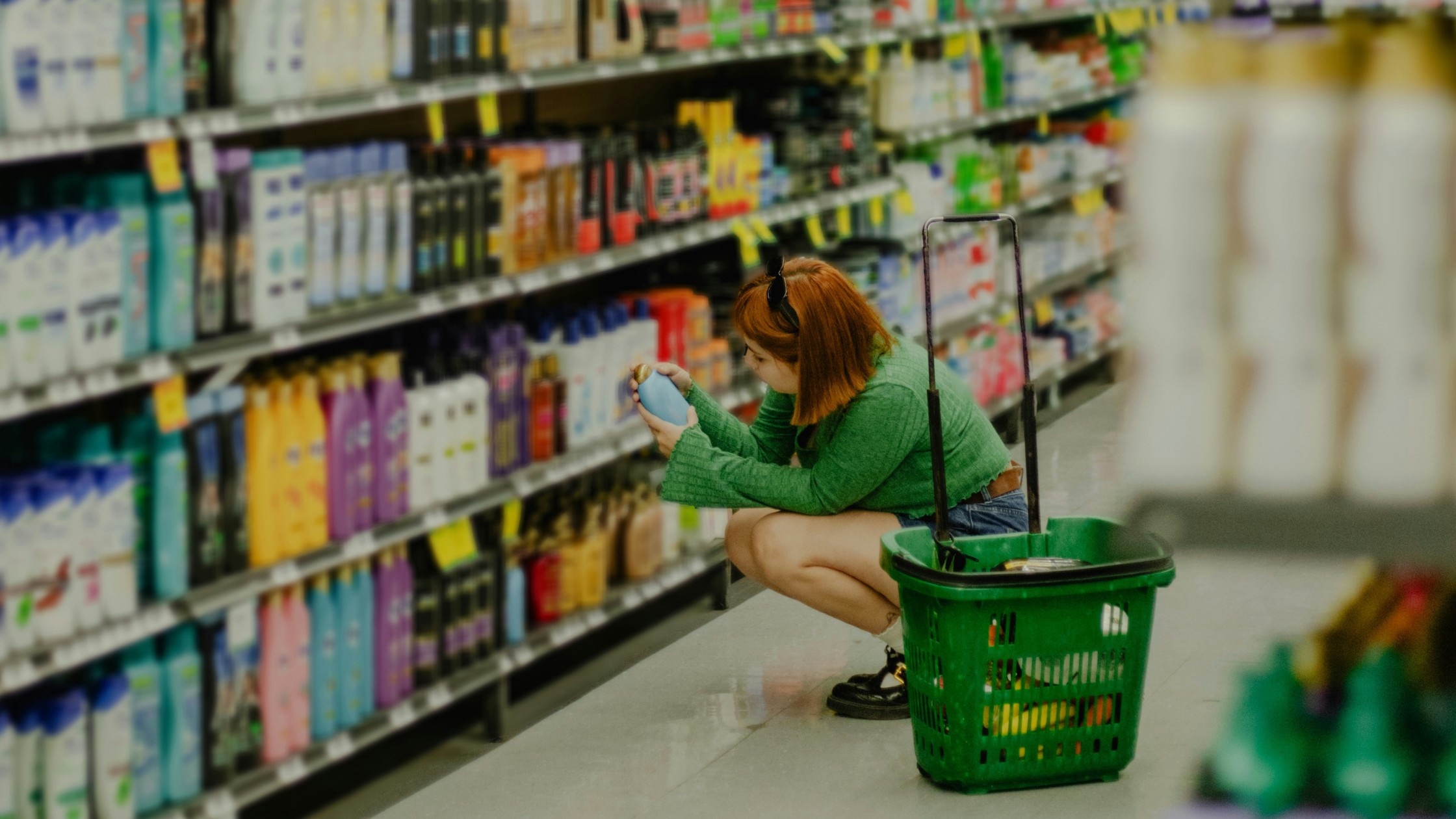 Woman examining a shampoo bottle in a supermarket aisle, representing DIY consumer insights research.